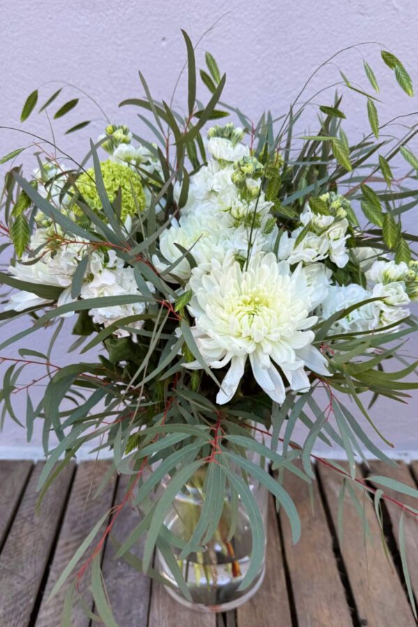 Naturlig bukett i hvitt og grønn med ulike blomster i glassvase